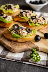 Baguette slices with tuna meat, onion, olives, egg and lettuce