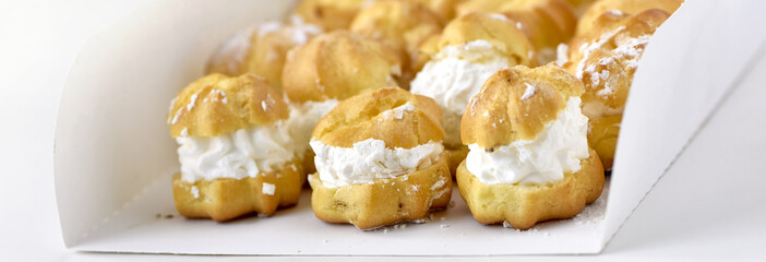 Profiteroles or cream puff cakes in white paper box