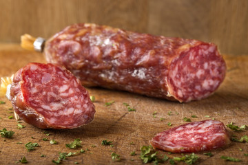 Italian salami on wooden cutting board with herbs