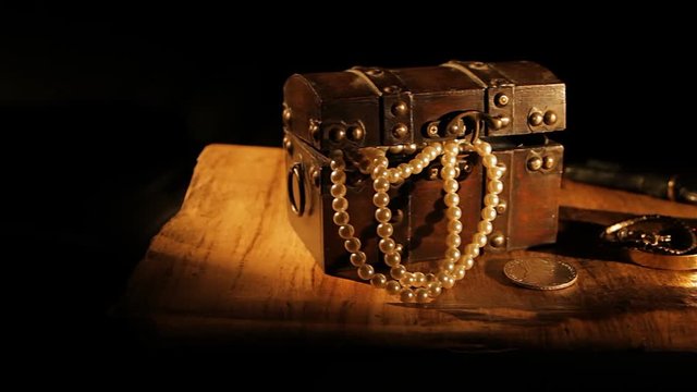 Dolly shot of a small treasure chest box with jewellery on a map