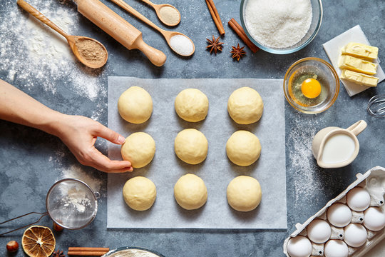 Baker hands preparing dough for buns recipe ingridients food flat lay on kitchen table background. Working with butter, milk, yeast, flour, eggs, sugar pastry or bakery cooking. Top view