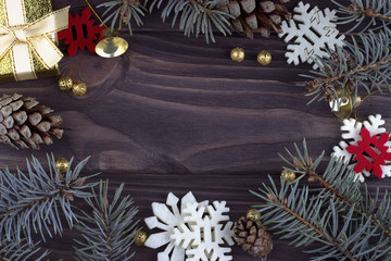 Christmas Xmas New Year holiday decoration with golden bells balls red white snowflakes natural fir branches and cones on dark wooden background, closeup, card consept, empty space