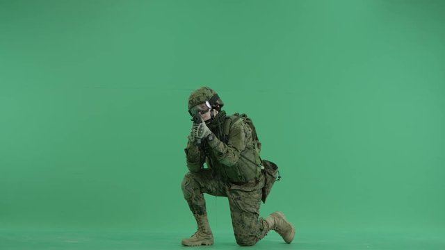 Soldier sitting and targeting and using radio at green screen