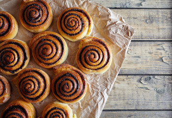 Freshly baked buns rolls with cinnamon and cocoa filling on parchment paper. Top view. Close-up. Kanelbulle - swedish Sweet Homemade christmas dessert.
