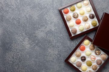 Various chocolate truffle candies in a box on gray stone background