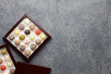 Various chocolate truffle candies in a box on gray stone background