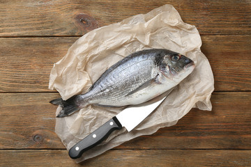 Raw fish with knife on wooden table
