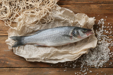 Raw fish with net and salt on wooden table