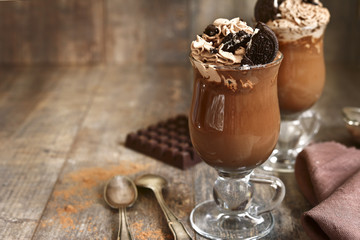 Two portions of hot chocolate with wipped cream and cookies.
