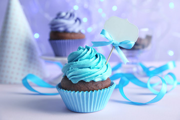 Birthday cupcake and ribbon on blurred lilac background