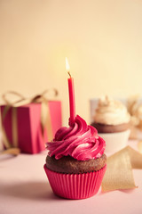 Birthday cupcake with gift box on light background
