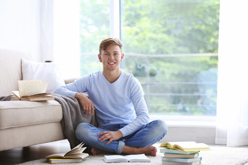 Young handsome man reading book at home