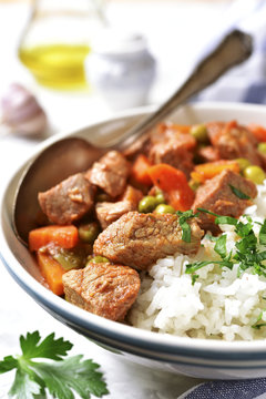 Veal stew served with rice on a light concrete background.