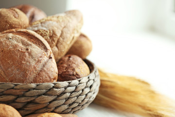 Lots of fresh bread in a basket on a table near the window