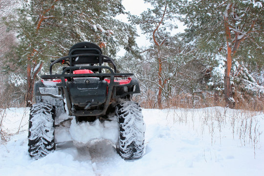 Snow covered quad bike in winter forest