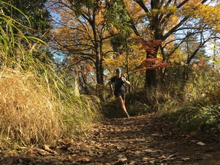 Autumn leaves and man running on country trail