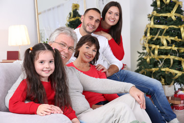 Happy family sitting on sofa in living room decorated for Christmas