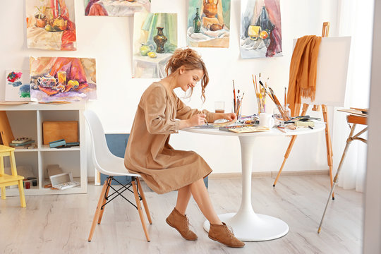 Young female artist painting picture in studio