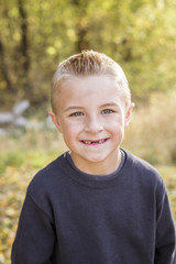 Cute, smiling, young boy portrait outdoors. He's got a big toothless smile