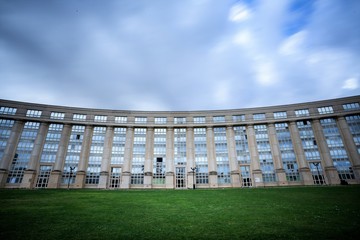 Naklejka premium un bâtiment architectural en arc de cercle avec pelouse verte et ciel bleu