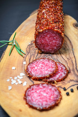 dried salami crusted in ground red pepper on dark background