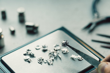 Jewelry tools. Jewellery. Goldsmith workplace, workspace on light background. Hand craft. Workshop. Manufacturing. Weigh-scales with granules of metal silver and platinum. Closeup. Toned