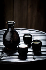 Obraz na płótnie Canvas Delicious sake in black ceramics on black table
