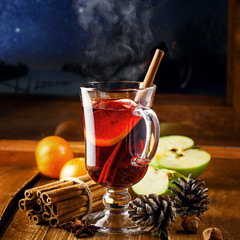 Traditional winter holiday alcoholic drink. Mulled wine with lemon slice on a table. Starry night...