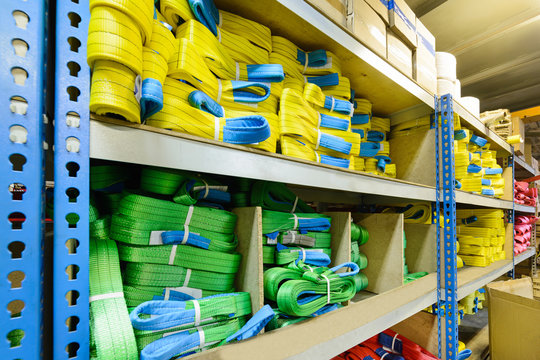 Green, yellow nylon soft lifting slings stacked in piles.