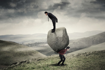Businessmen with stone at hill © Creativa Images