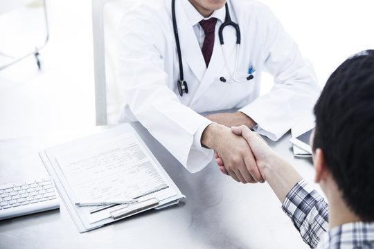 The doctor is shaking hands with the patient in the examination room