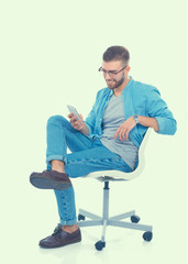 Young man sitting on chair and using mobile phone