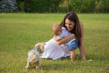 Happy mother and child with dog on grass in park