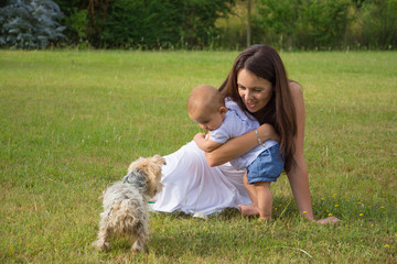 Happy mother and child with dog on grass in park