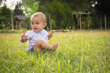 happy young baby child sittng on grass on beautiful summer day i
