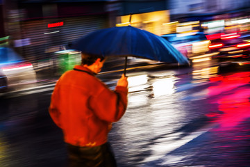 man with umbrella walking at night in the city