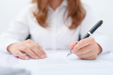 Business women filling contract at desk.