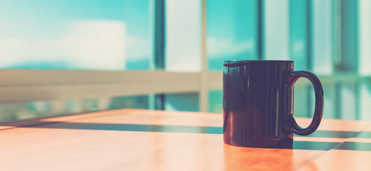 Black cup of coffee in brightly lit room