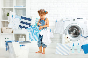 child fun happy little girl  to wash clothes and laughs in laund