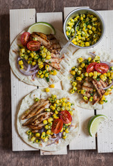 Grilled chicken and corn salsa tortilla on a wooden board. Top view, flat lay