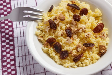 Cooked millet groats with walnuts on white plate, healthy food and nutrition