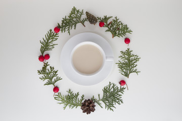 Christmas composition. Cup of coffee with green thuja twigs and red wild rose fruits on white background. Top view, flat lay. Copy space for text