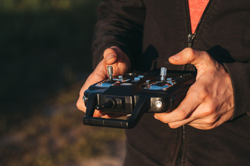 Man holding remote controller in hands close-up. Male hands piloting rc car, drone or helicopter. Pilot running his vehicle with transmitter outdoor, free space