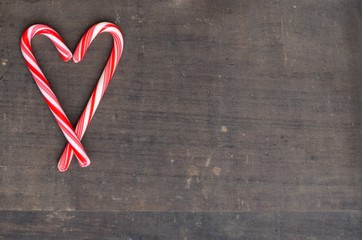 Red and white candy canes heart on wooden background