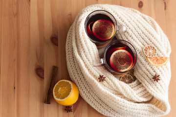 Seasonal and holidays concept . Christmas mulled wine with beautiful orange slices inside the glass , covered with warm white scarf . Very warm and cozy atmosphere