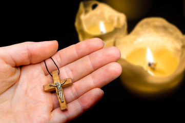 Fototapeta premium Female hand with wooden cross on candles background