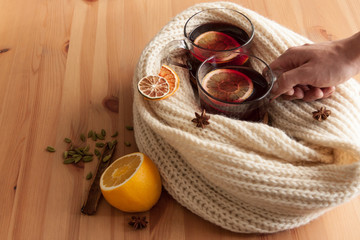 Seasonal and holidays concept . Christmas mulled wine with beautiful orange slices inside the glass , covered with warm white scarf . Very warm and cozy atmosphere