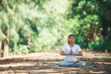 Young asian woman doing yoga in the morning at the park. Healthy