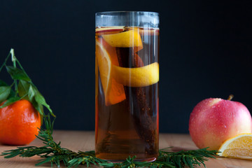 Glass with Seasonal warming drink.Cinnamon,lemon zest and some fruits.