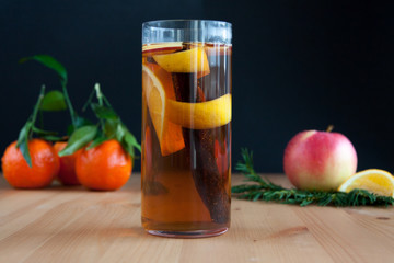 Glass with Seasonal warming drink.Cinnamon,lemon zest and some fruits.